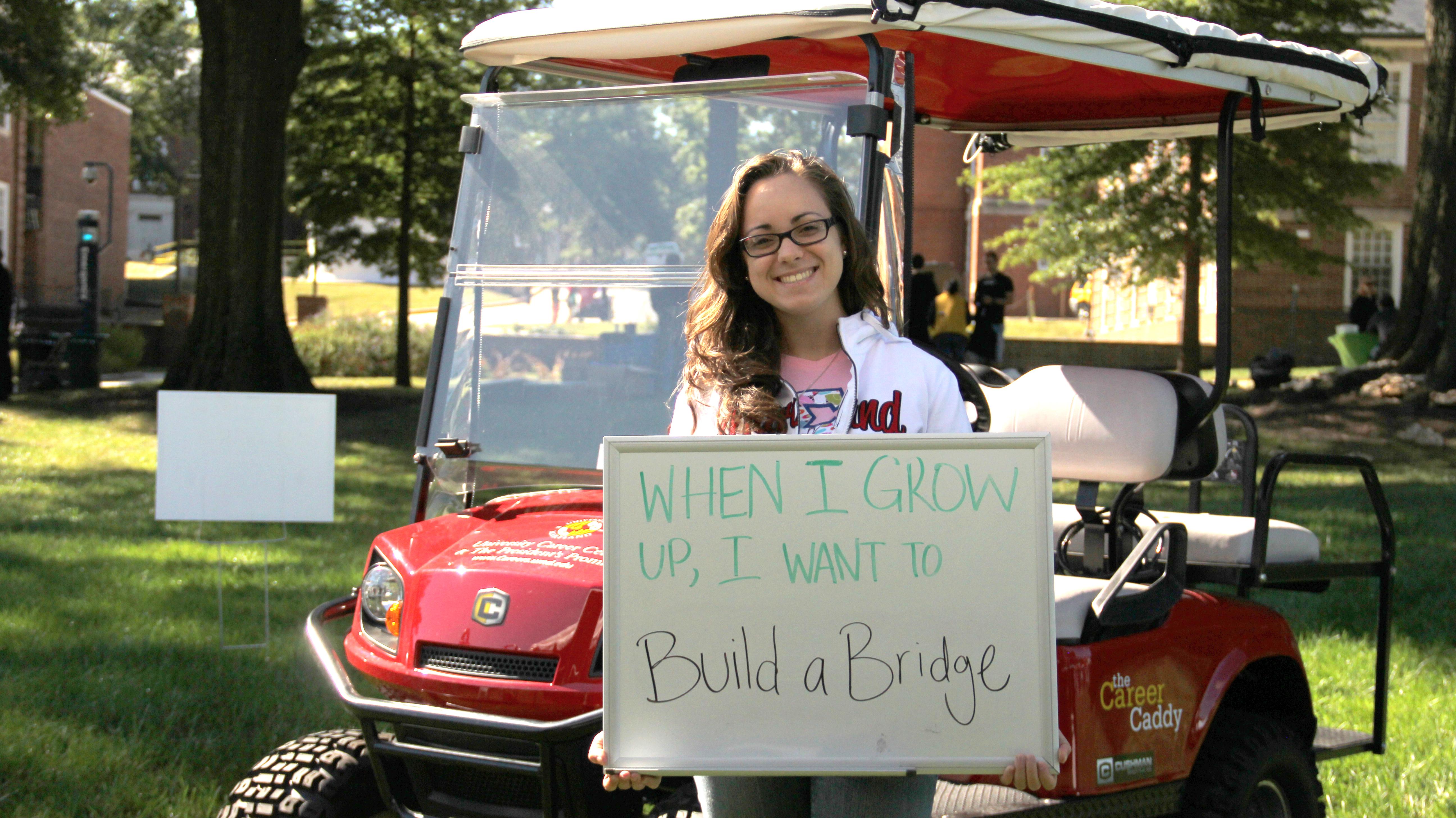 Photo: Young woman holding sign: "When I grow up, I want to Build a Bridge"