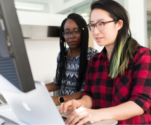 Two women working together at a computer.