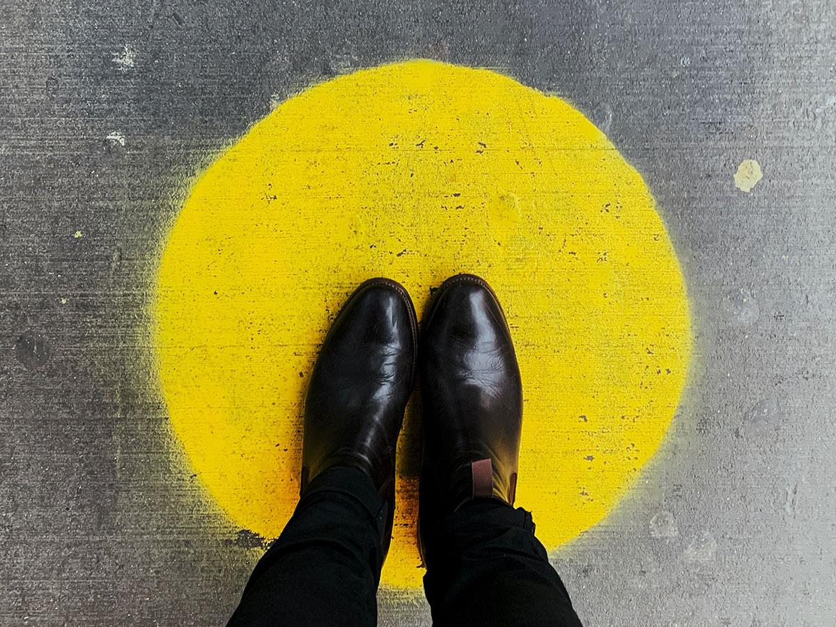 Black shoes standing on yellow spray paint dot