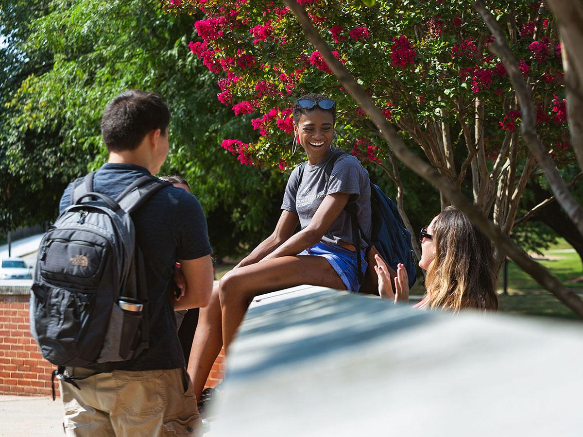 Three students laughing together outsite