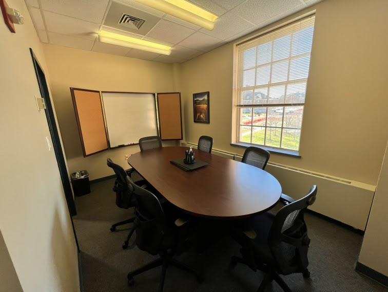 Wooden rounded conference table in a small room with window