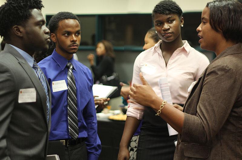 Four people in business casual standing together in discussion