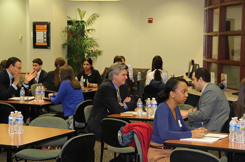 Multiple pairs of students and professional recruiters engaged in face-to-face interviews inside the career center.