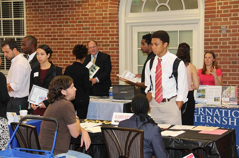 Students and professional representatives interacting at tables during an indoor career fair.