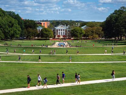 Students walking along sidewalk in front of campus building