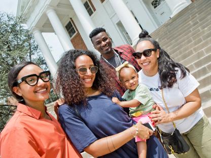 A family of 5 smiling and standing outside