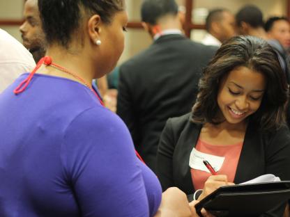 Smiling student writing down notes from a conversation with employer