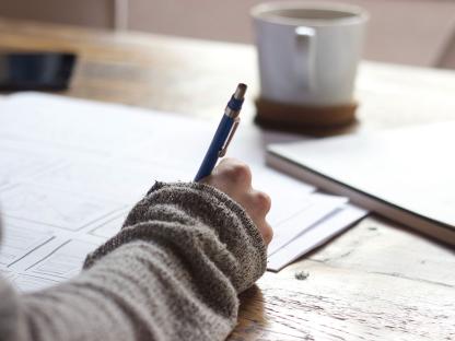 Person holding pen and writing down notes