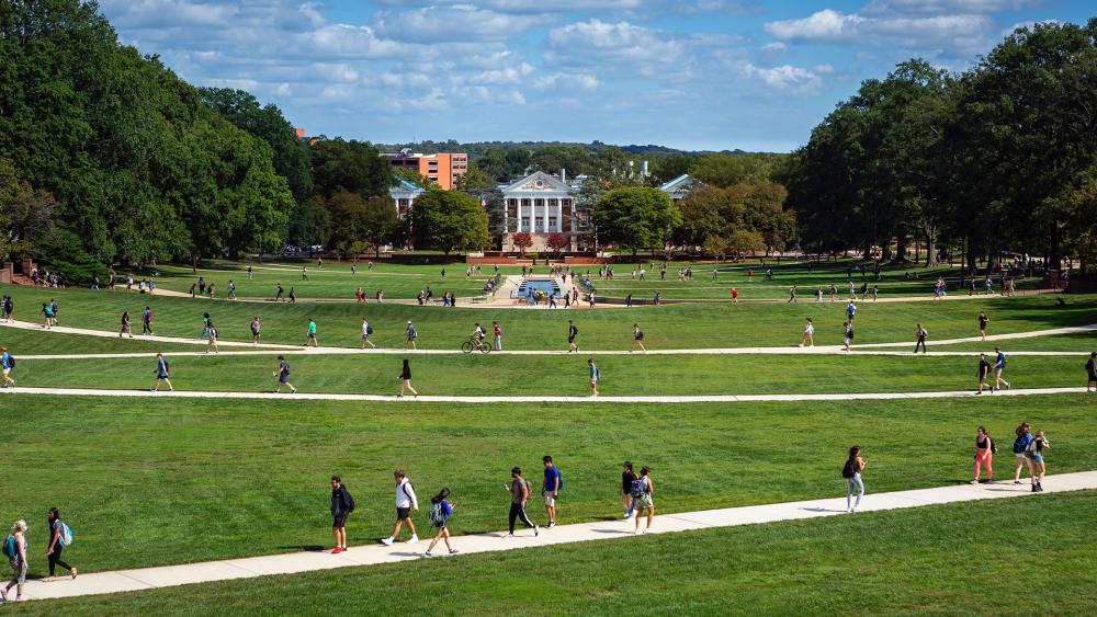 View of green fields in front of campus and students walking by